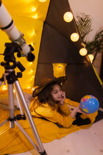 istock Small girl using earth globe at home living room in a tent. 1208758016