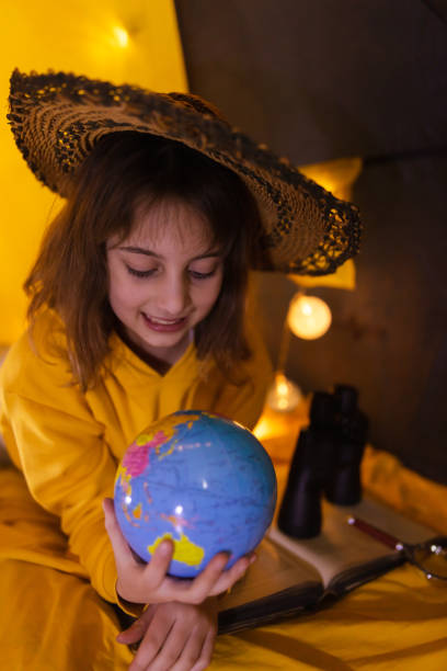 istock Small girl using earth globe at home living room in a tent. 1208758032