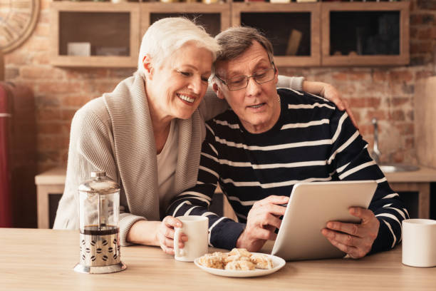 istock Happy Senior Couple Using Digital Tablet And Drinking Coffee In Kitchen 1208759301