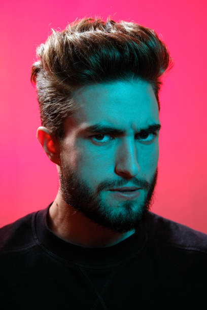 istock Young handsome model posing in a studio in a trendy neon light. Vibrant color. Bright colorful light effects. Disco style. 1208761747