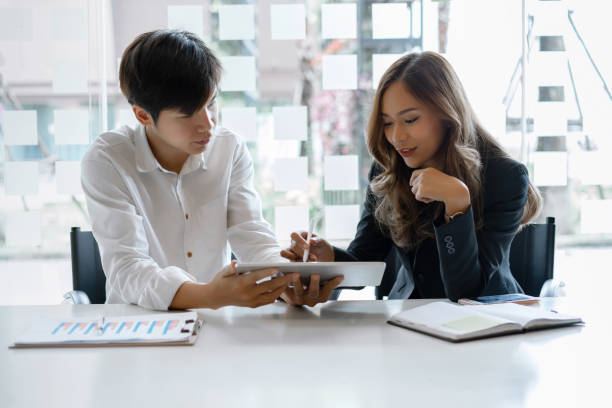 istock Startup young asian caucasian colleagues discussing work together on tablet, male worker talking to female coworker collaboration concept 1208761869