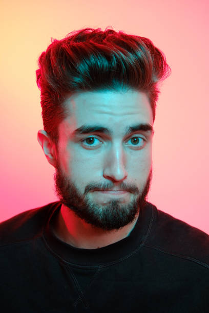 istock Young handsome model posing in a studio in a trendy neon light. Vibrant color. Bright colorful light effects. Disco style. 1208762049
