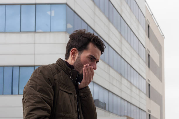 istock Man coughing in the city 1208762683