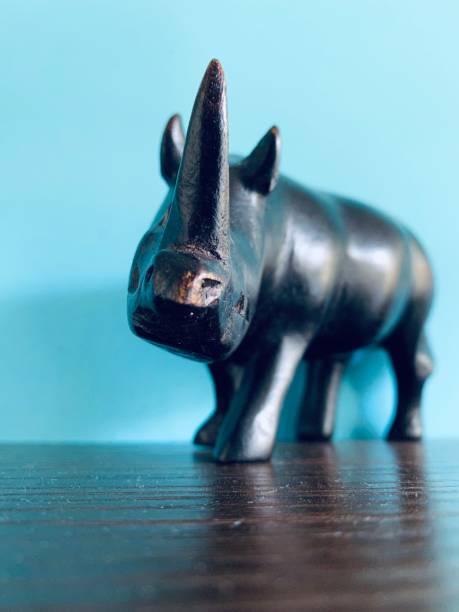 istock Black wooden rhino and a white elephant on blue background 1208764414