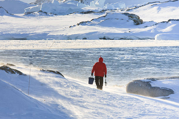 Man goes fishing Man goes fishing in a snowstorm. Antarctica man ice fishing stock pictures, royalty-free photos & images