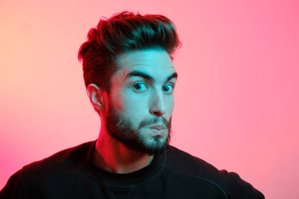 istock Young handsome model posing in a studio in a trendy neon light. Vibrant color. Bright colorful light effects. Disco style. 1208765681