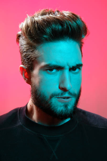 istock Young handsome model posing in a studio in a trendy neon light. Vibrant color. Bright colorful light effects. Disco style. 1208765738
