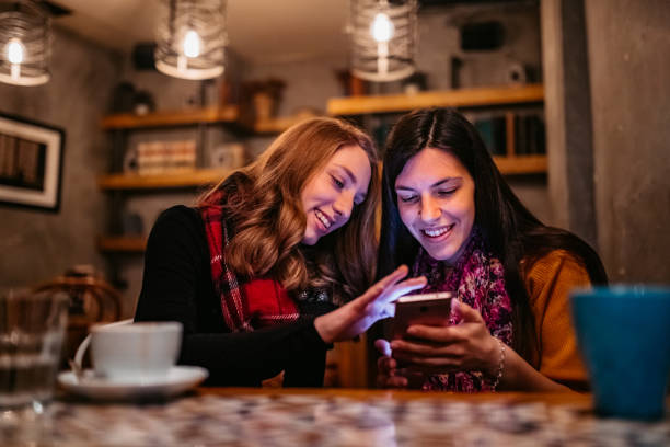 istock Two female friends using phone on coffee break 1208766097