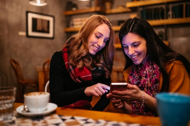 istock Two female friends using phone on coffee break 1208766146