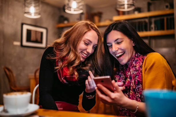 istock Two female friends using phone on coffee break 1208766195