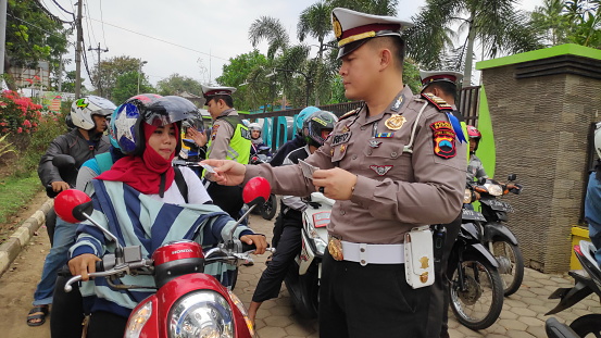 Three cheerful thai tourist police officers are standing  on  promenade in Nong Khai in early morning and sunrise at Mekong river in North Thailand. There are two men and one woman. In background are a few people and preparations for a local cycling event