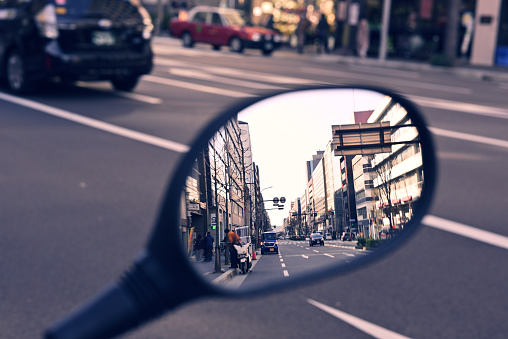 a side mirror of a motor bike is reflecting Karasuma street in Kyoto