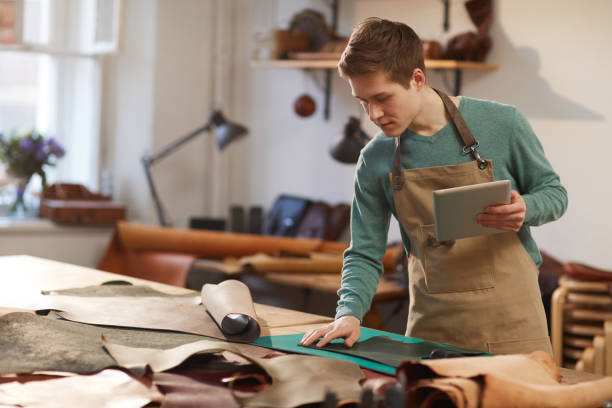 istock Male Artisan Choosing Piece Of Leather 1208768135