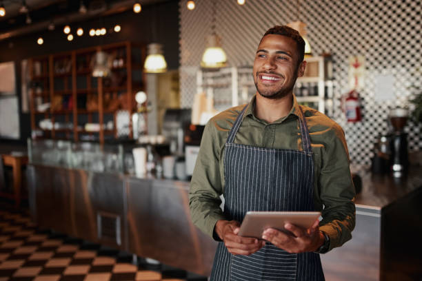 wesoły młody mężczyzna właściciel trzyma cyfrowy tablet stojący w kawiarni - cafeteria food service business zdjęcia i obrazy z banku zdjęć