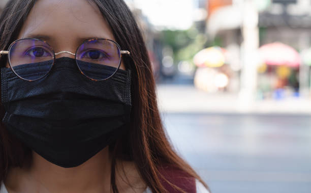 giovane ragazza asiatica diversificata all'aperto che indossa una maschera chirurgica protettiva per proteggere dall'inquinamento e dalle malattie infettive - foreign and commonwealth office foto e immagini stock