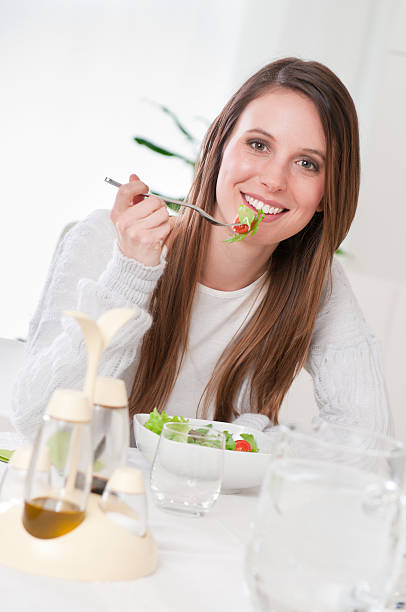 szczęśliwa kobieta jedzenie sałatka - vegan food cheerful vertical indoors zdjęcia i obrazy z banku zdjęć