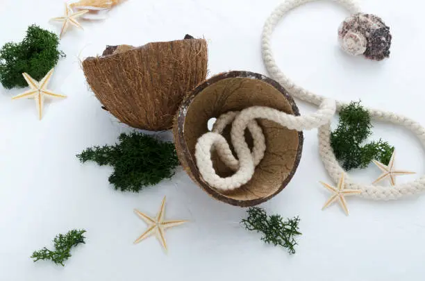Top view of coconut shell, fresh exotic plant, marine rope, starfish on the white surface.Concept of summer vacation and relax