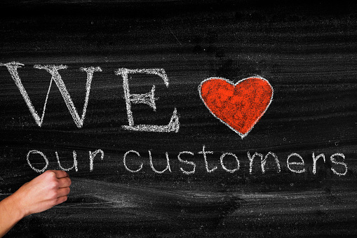 We love our customers,business concept on blackboard
