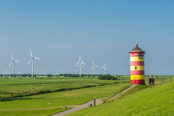 Pilsum Lighthouse with Wind Turbines, North Sea, East Frisia, Germany The famous Pilsum Lighthouse with wind turbines in the background near the East Frisian village of Greetsiel on the German North Sea coast of Lower Saxony. The lighthouse was built in 1891 and became famous as one of the central locations of the movie Otto – Der Außerfriesische ("Otto – the Outer Frisian") by the German comedian Otto Waalkes. german north sea region stock pictures, royalty-free photos & images