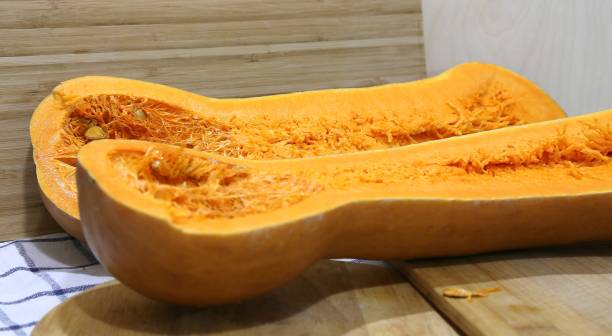 istock Incredible large cut into two pieces bright very orange long-shaped pumpkin with flesh inside and seeds on cutting boards 1208775514