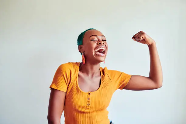 Shot of a beautiful young woman flexing her muscles against a white background