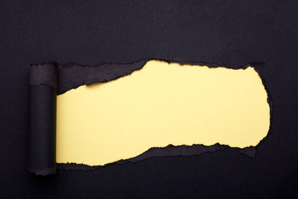 istock Hole in the black paper. Torn. Yellow paper background. Abstract background. 1208782366