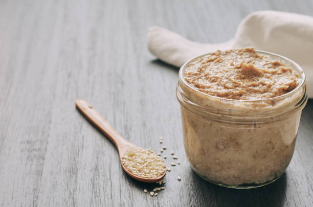 istock Homemade tahini, sesame paste with its seeds on a black background 1208784192