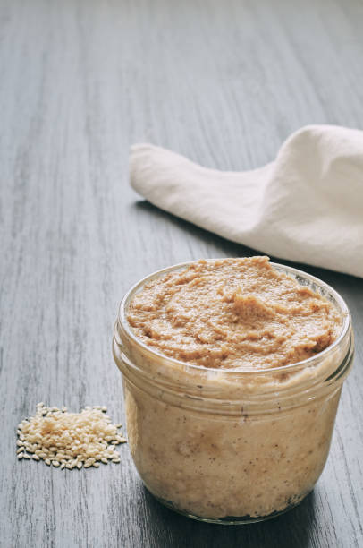 istock Homemade tahini, sesame paste with its seeds on a black background 1208784194