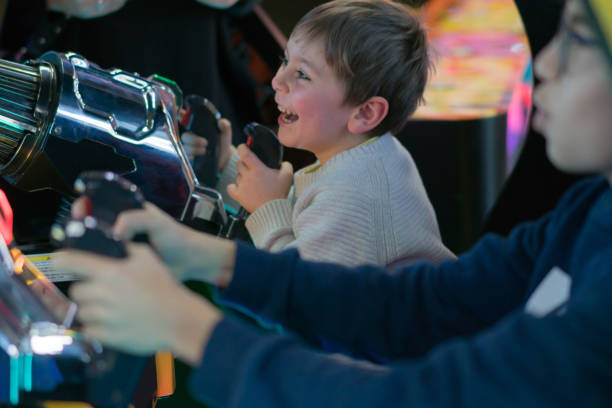 Happy brothers playing arcade game Happy brothers playing arcade game arcade photos stock pictures, royalty-free photos & images