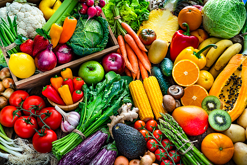High angle view of a large assortment of healthy fresh organic fruits and vegetables. The composition includes cabbage, carrots, onion, tomatoes, raw potato, avocado, asparagus, eggplant, ginger, green beans, celery, cucumber, broccoli, lettuce, spinach, radish, lemon, apples, strawberries, pineapple, papaya, mango, banana, grape fruit, oranges, kiwi fruit among others. The composition is at the left of an horizontal frame leaving useful copy space for text and/or logo at the right. High resolution 42Mp studio digital capture taken with SONY A7rII and Zeiss Batis 40mm F2.0 CF lens