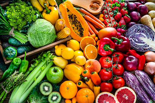 High angle view of a large assortment of healthy fresh rainbow colored organic fruits and vegetables. The composition includes cabbage, carrots, onion, tomatoes, raw potato, avocado, asparagus, eggplant, celery, cucumber, broccoli, squash, lettuce, spinach, lemon, apples, pear, strawberries, papaya, mango, banana, grape fruit, oranges, kiwi fruit among others. The composition is at the left of an horizontal frame leaving useful copy space for text and/or logo at the right. High resolution 42Mp studio digital capture taken with SONY A7rII and Zeiss Batis 40mm F2.0 CF lens