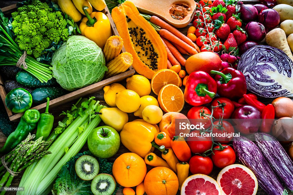 Healthy fresh rainbow colored fruits and vegetables background High angle view of a large assortment of healthy fresh rainbow colored organic fruits and vegetables. The composition includes cabbage, carrots, onion, tomatoes, raw potato, avocado, asparagus, eggplant, celery, cucumber, broccoli, squash, lettuce, spinach, lemon, apples, pear, strawberries, papaya, mango, banana, grape fruit, oranges, kiwi fruit among others. The composition is at the left of an horizontal frame leaving useful copy space for text and/or logo at the right. High resolution 42Mp studio digital capture taken with SONY A7rII and Zeiss Batis 40mm F2.0 CF lens Vegetable Stock Photo