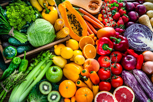 Healthy fresh rainbow colored fruits and vegetables background High angle view of a large assortment of healthy fresh rainbow colored organic fruits and vegetables. The composition includes cabbage, carrots, onion, tomatoes, raw potato, avocado, asparagus, eggplant, celery, cucumber, broccoli, squash, lettuce, spinach, lemon, apples, pear, strawberries, papaya, mango, banana, grape fruit, oranges, kiwi fruit among others. The composition is at the left of an horizontal frame leaving useful copy space for text and/or logo at the right. High resolution 42Mp studio digital capture taken with SONY A7rII and Zeiss Batis 40mm F2.0 CF lens lettuce photos stock pictures, royalty-free photos & images