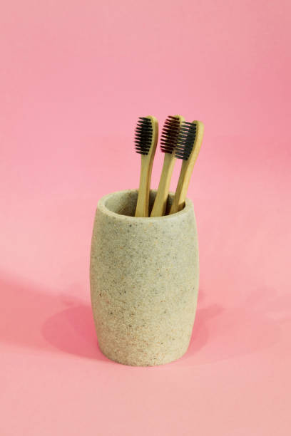 istock Eco toothbrushes in a glass on pink background 1208791326
