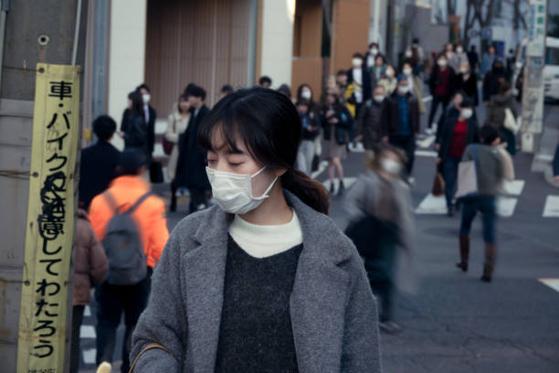 asiatische frau trägt gesichtsmaske auf der straße zur hauptverkehrszeit - pollenkorn stock-fotos und bilder