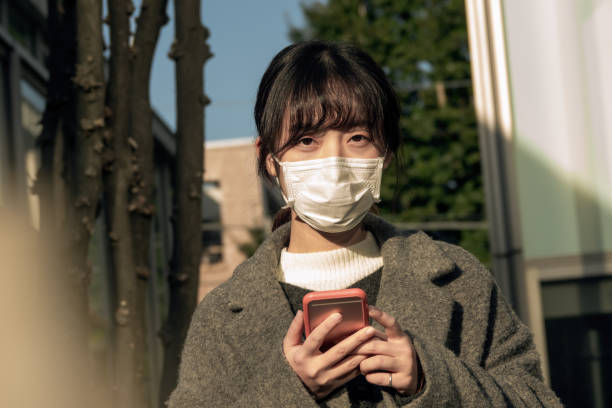 asiatische frau trägt gesichtsmaske auf der straße - pollenkorn stock-fotos und bilder