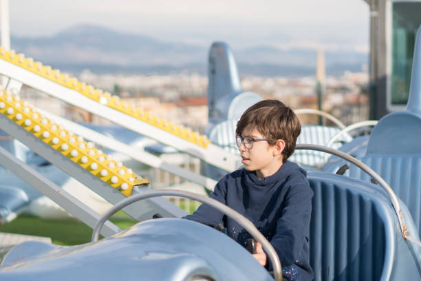 Happy boy fly on airplane attraction in amusement park