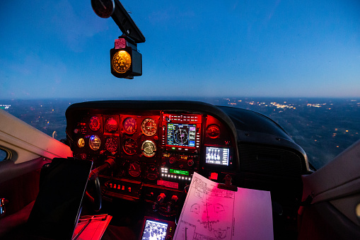 The red glow of an airplane instrument panel contrasts with the deep blue sky in this in-flight view at dawn.