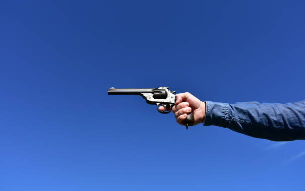 istock Man holding a .44 or .45 caliber revolver outdoors with blue sky. 1208795503