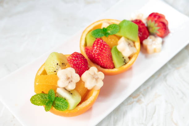 The bowl is made of orange and filled with different fruits