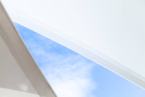 하얀 돛 모양의 차양은 밝은 푸른 하늘 아래 - shade sail awning textile 뉴스 사진 이미지