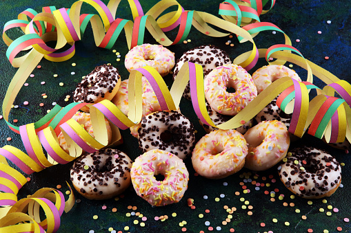 celebration donuts with colorful party streamers and confetti on rustic background
