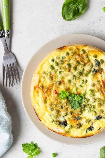 istock Spinach and green pea quiche, tart or pie with ingredients for baking. Light grey background, copy space. 1208804361