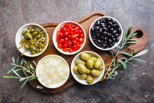 Italian appetizer from above. Mediterranean snack assortment. Black and green olives, capers, olive oil, onion, pepper and garlic top view.