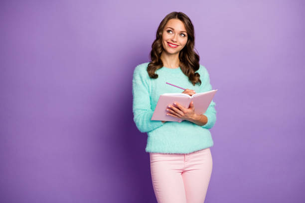 istock Photo of beautiful wavy lady hold planner write essay imagination flight look empty space responsible student wear pastel fuzzy sweater pink trousers isolated purple color background 1208804576