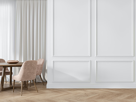 Interior blanco clásico moderno con molduras, paneles, mesa de comedor, sillas rosadas, suelo de madera. photo