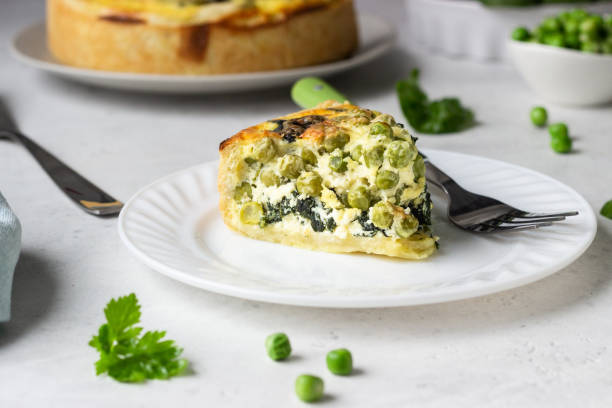 istock Spinach and green pea quiche, tart or pie with ingredients for baking. Light grey background, copy space. 1208807601