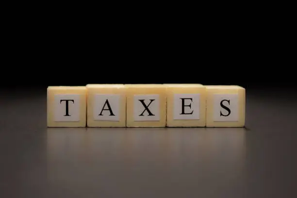 The word TAXES written on  wooden cubes isolated on a black background
