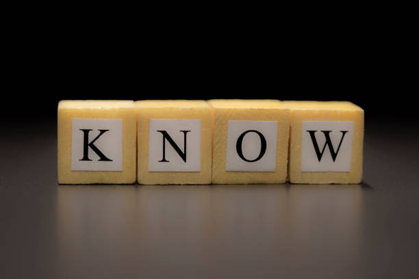 The word KNOW written on wooden cubes isolated on a black background...