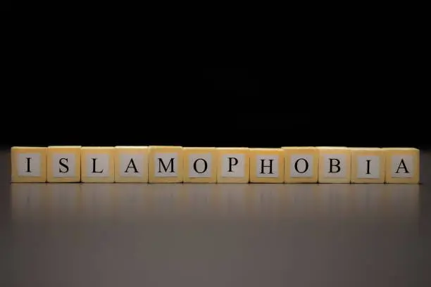 Photo of ISLAMOPHOBIA written on wooden cubes isolated on a black background...